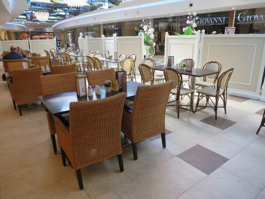 Gemütliche Tische mit Korbstühlen im Gastraum des Cafés