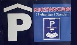 Schild „Kurzparkzone (Tiefgarage 2 Stunden)“ mit Parkuhr-Symbol